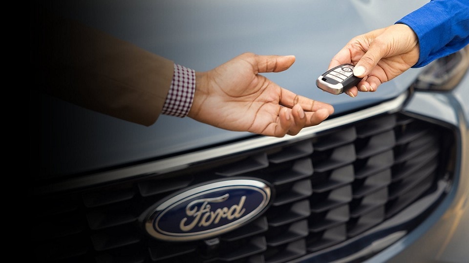 Keys are handed from a Ford Dealer to a customer in front of a Ford vehicle