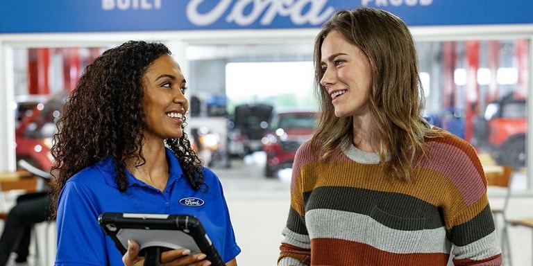A Ford representative is having a friendly conversation with a customer inside a Ford dealership