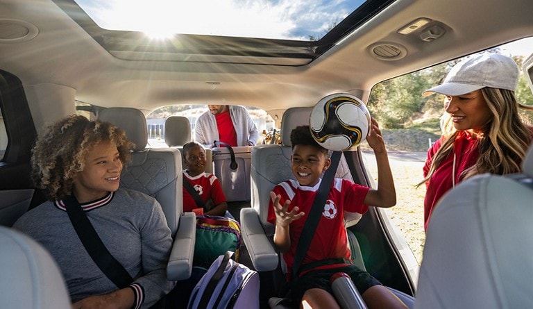 It’s a sunny day and a group of smiling kids is seated in a Ford vehicle with the doors open, dressed to play soccer