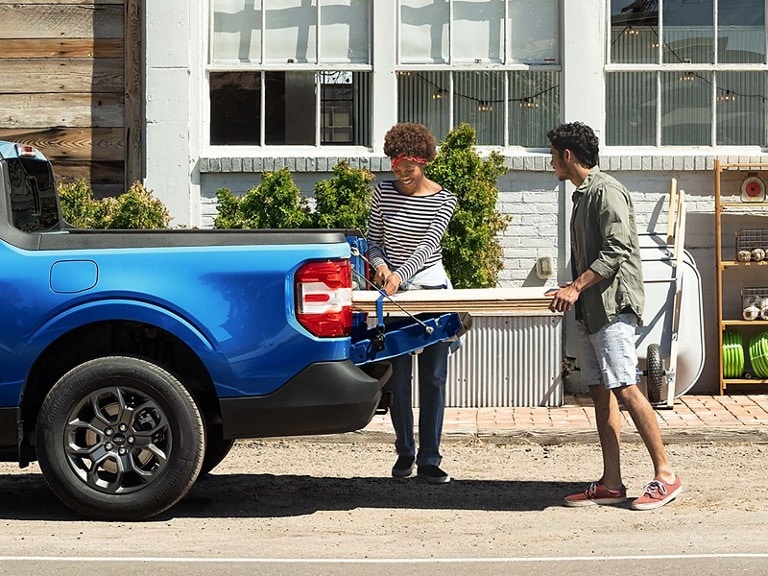 A couple load up lumber in the back of their Maverick® pickup
