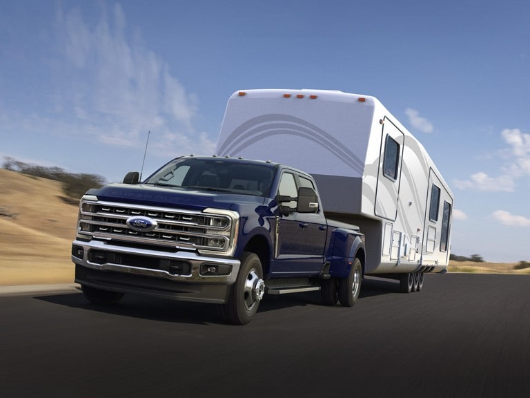 2026 Ford Super Duty® F-350 Lariat® in Argon Blue pulling a trailer down a road