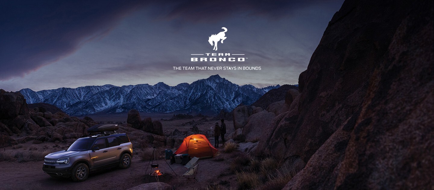 Team Bronco - the team that never stays in bounds - couple camping in a rugged terrain beside a bronco sport  at night