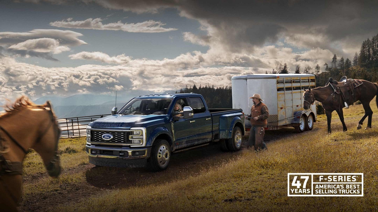 A man riding a horse toward a 2023 Ford Super Duty® F-450® King Ranch® DRW pickup hitched to a horse trailer