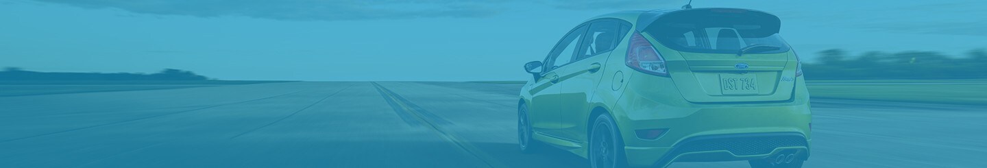 Se muestra imagen trasera de un Ford Fiesta en Outrageous Green Metallic pasando por la carretera
