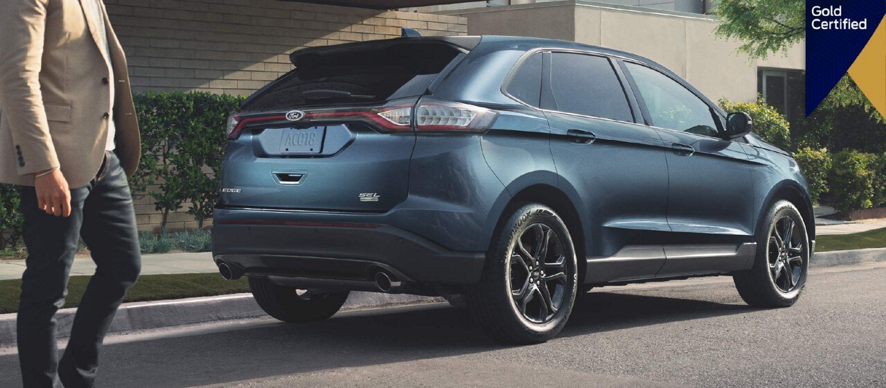 Person walking next to a parked Ford vehicle.