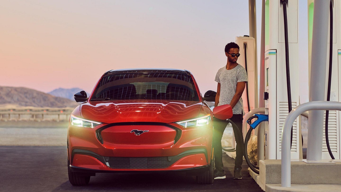 Un conductor carga una Ford Mustang® Mach-E® 2023 red en una estación de carga pública