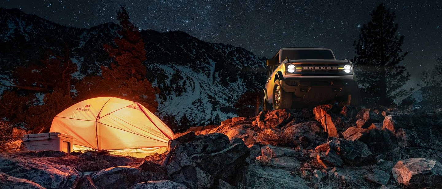 Two-door 2023 Ford Bronco® Big Bend® in Oxford White parked by a campsite at night