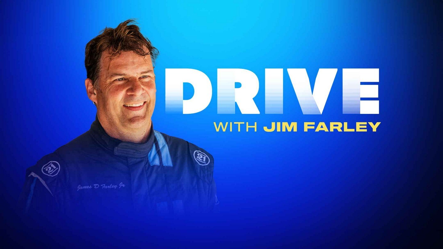 Ford CEO Jim Farley in a Ford racing suit smiling and looking exhilarated.