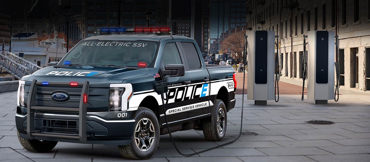 2023 Ford F-150®️ Lightning™️ Pro SSV truck parked near a city boat dock being charged by a charge station