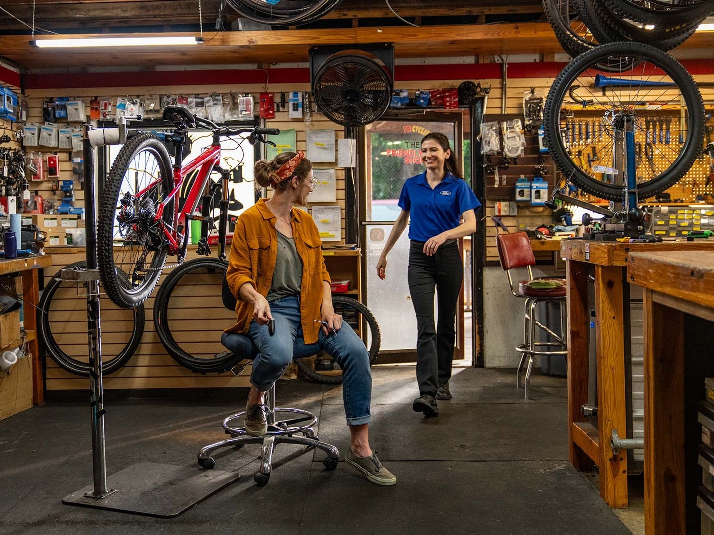 Un técnico de servicio Ford ingresa a una tienda de bicicletas y recoge las llaves de un empleado para realizar el servicio de Recogida y Entrega