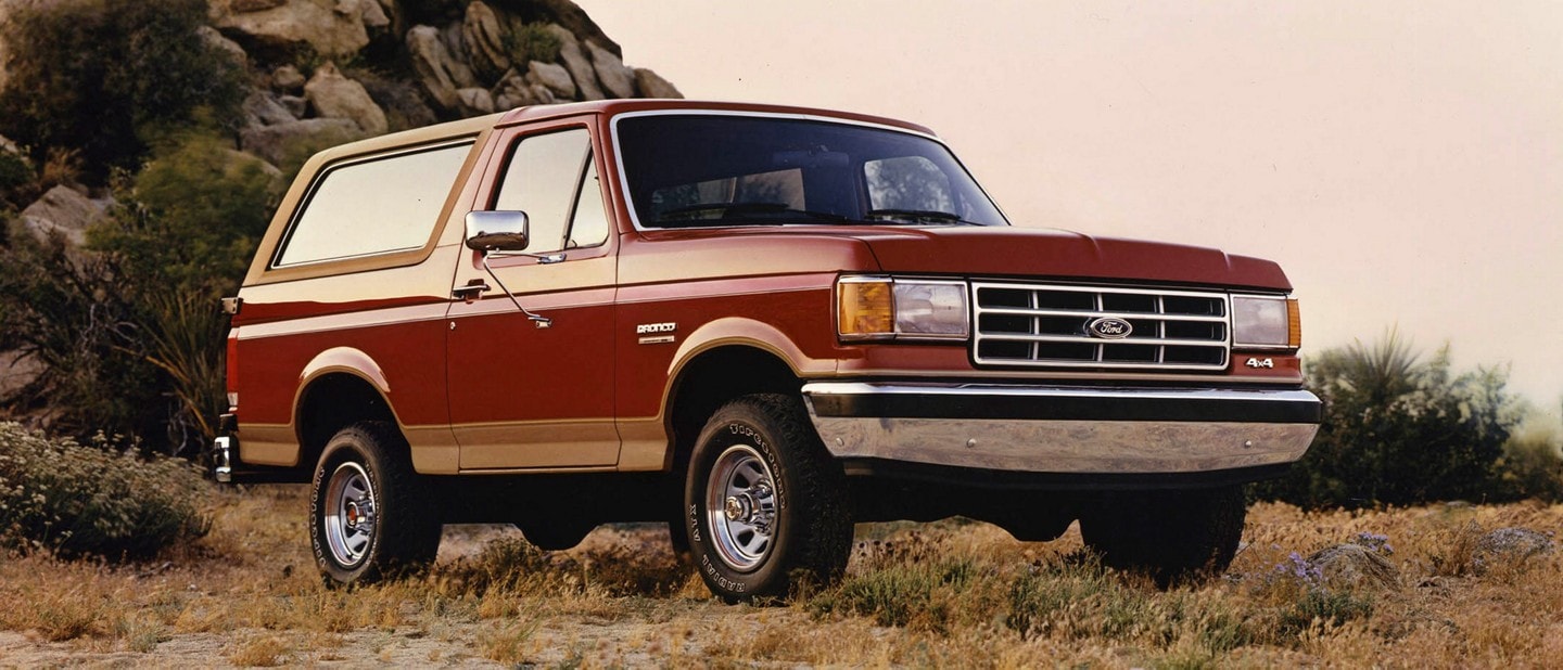 Fourth and fifth generation 1987 Ford Bronco parked on street.
