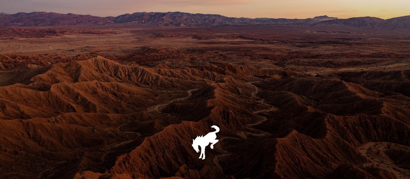 Cimas de montañas con colinas de terreno desparejo y logotipo bronco  