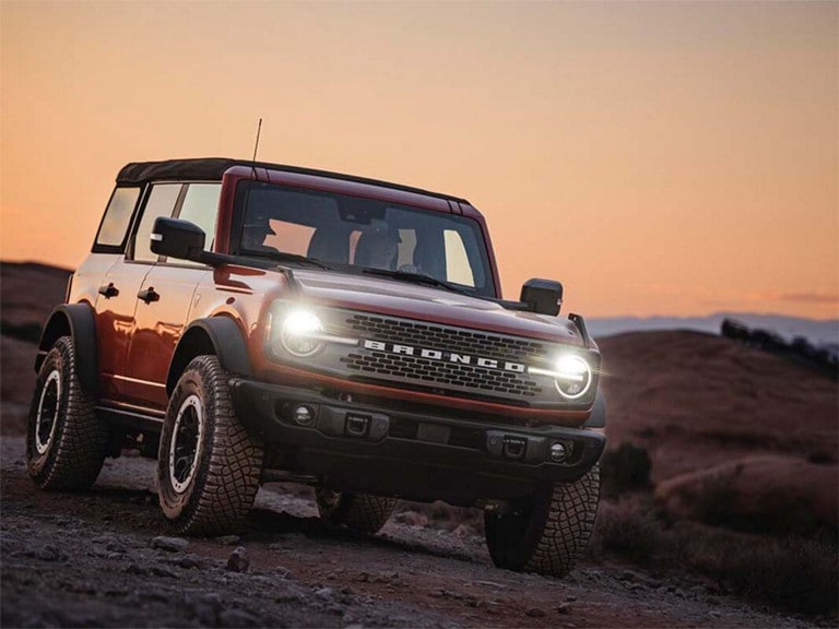 Persona conduciendo un modelo Ford Bronco® Badlands® 2024 de cuatro puertas al atardecer