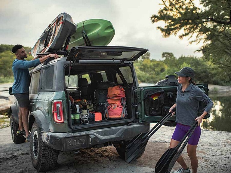 Dos personas cargando equipos en un modelo Ford Bronco® Outer Banks® 2024 estacionado