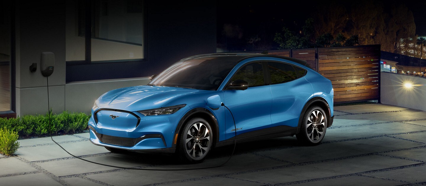 Ford Mustang Mach-E 2023 conectada a una estación de carga en casa fuera de una vivienda de lujo