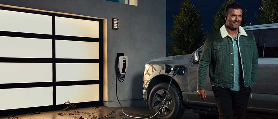 Un hombre al lado de una Ford F-150® Lightning™ 2023 cargándola en su casa