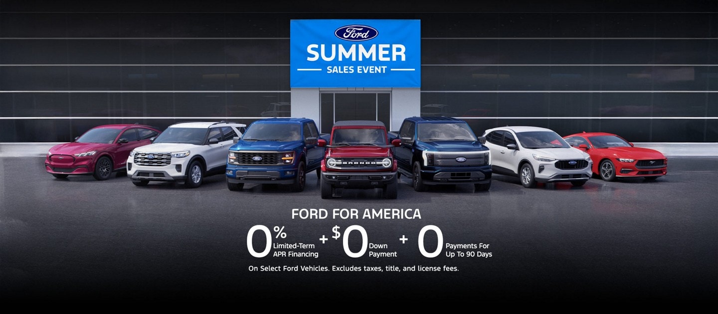 A lineup of Ford vehicles in front of a Ford dealership that displays a Ford Summer Sales Event banner