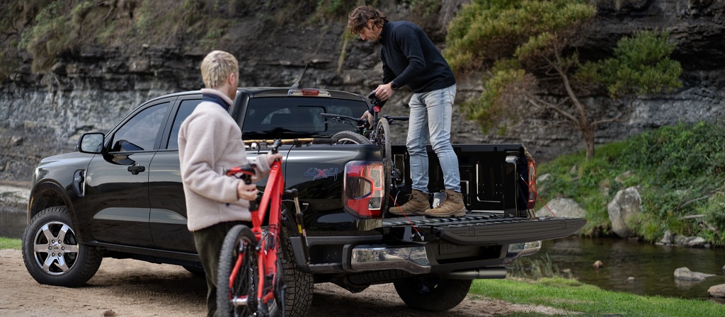 Two people loading gear into the bed of a 2025 Ford Ranger® pickup in Bronze Metallic