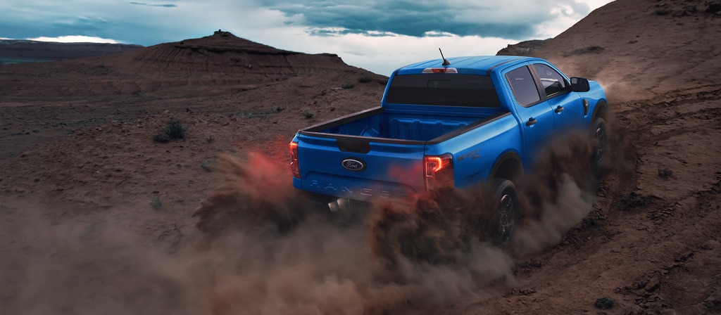 Rear view of a 2025 Ford Ranger® pickup being driven off kicking up dust
