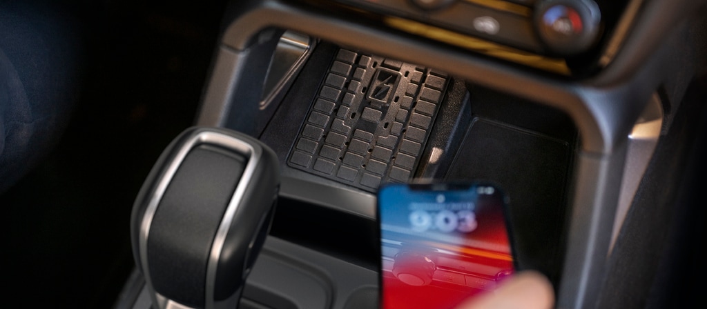 Close-up of a person placing a phone on the wireless charger in the 2025 Ford Ranger®