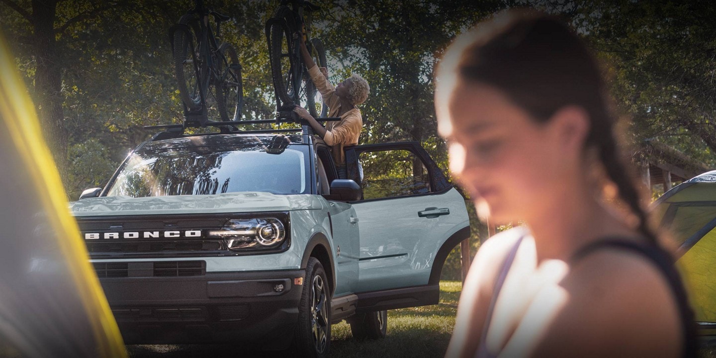 2024 Ford Bronco Sport® model in background, with a woman standing outside near the vehicle