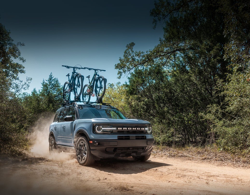 Una Ford Bronco® Sport 2024 con bicicletas en el techo andando por un sendero de tierra
