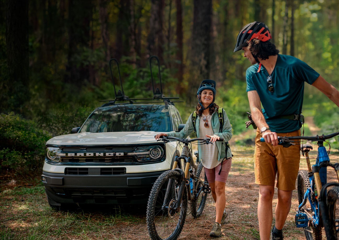 2024 Ford Bronco® Sport SUV parked in the background, with two people standing outside the vehicle with bikes