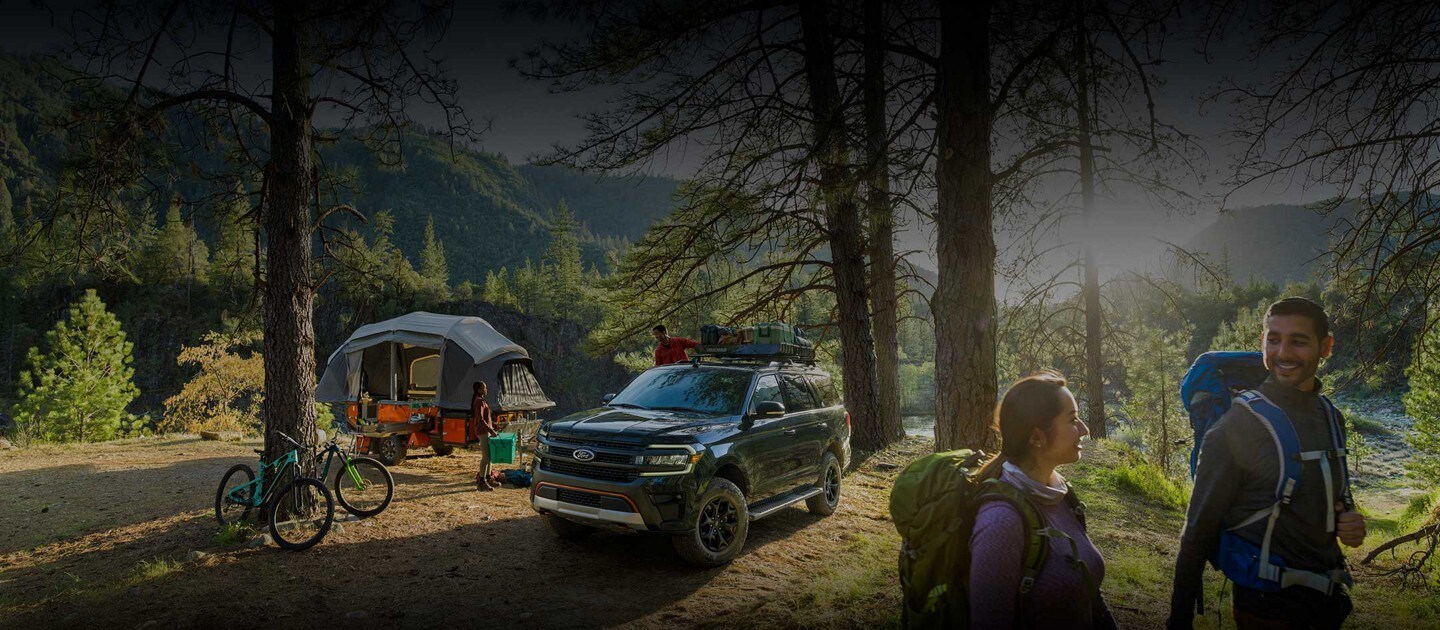 Imágenes laterales de una SUV Ford Expedition 2023 andando por un camino de tierra y estacionada en un campamento