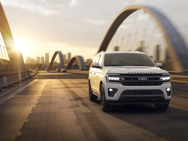 A 2024 Ford Expedition® is being driven over a bridge on a city highway