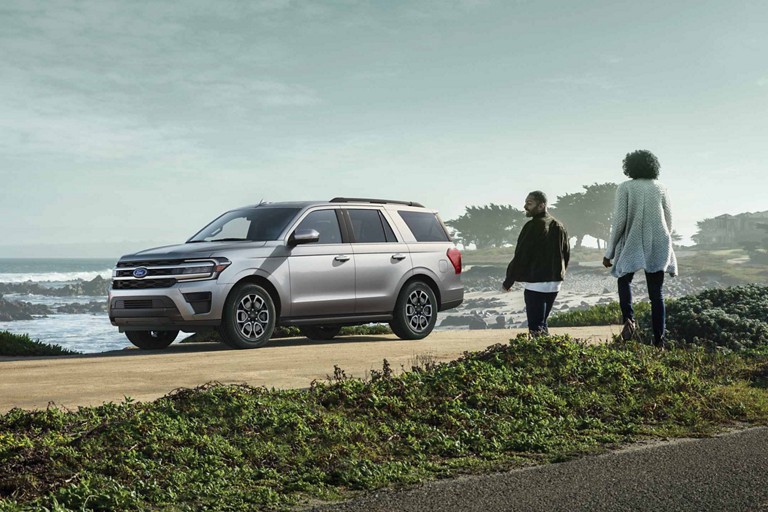 Two people approach a 2024 Expedition parked next to a body of water