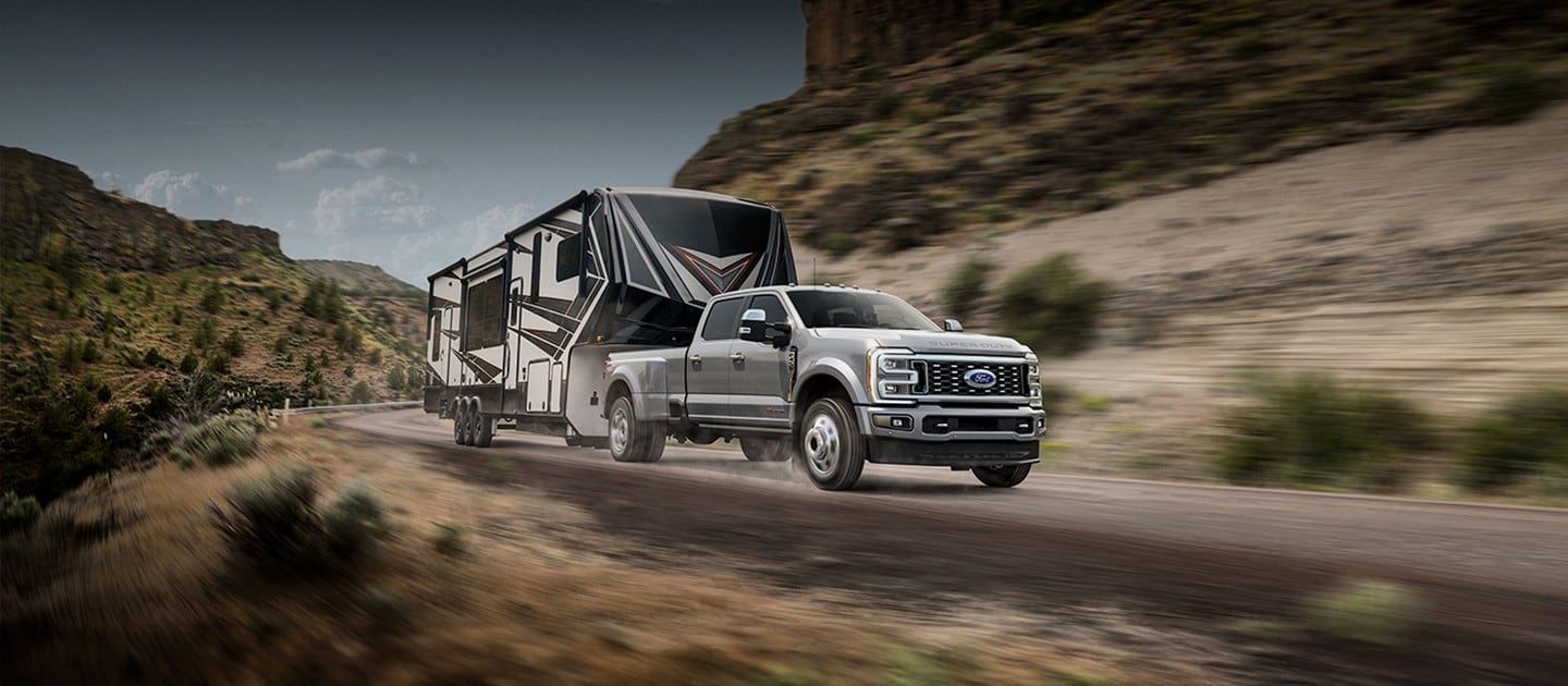 2024 Ford Super Duty® F-450® Limited DRW model pulling a camper trailer on a mountain road