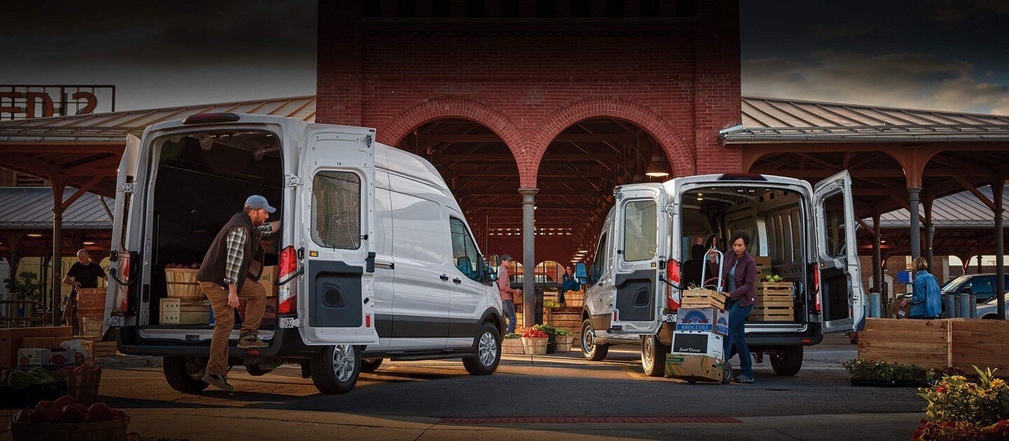 Two 2023 Ford Transit® vans parked at a market unloading cargo