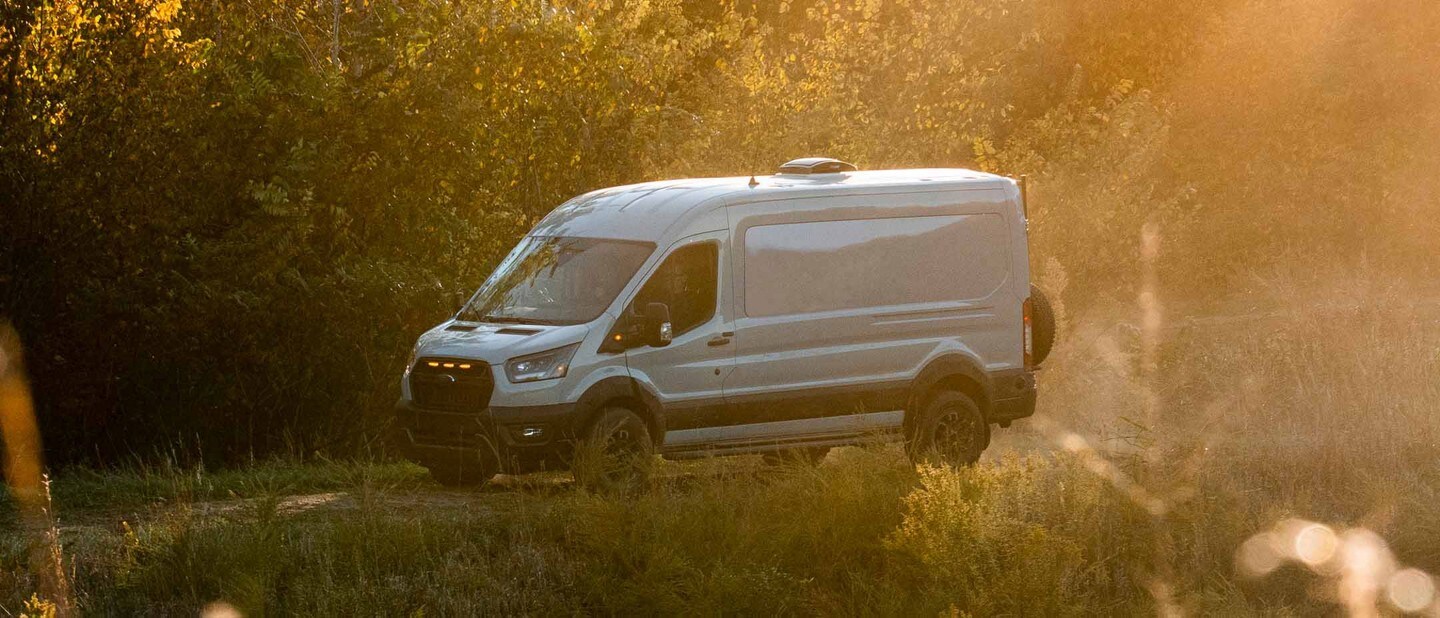 Una Ford Transit Trail™ Van 2023 andando por un camino de bosque